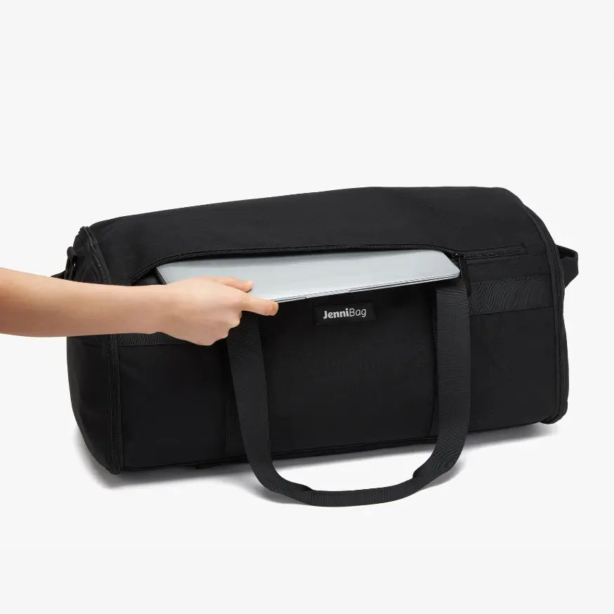 The padded 15-inch laptop sleeve, shown with a laptop sliding into its own zippered compartment separate from the main packing area